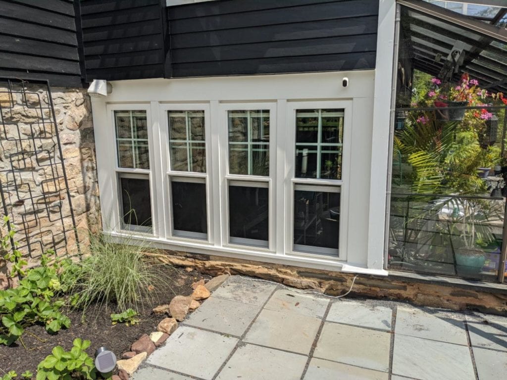 black roof with white windows and door with stone walls of house